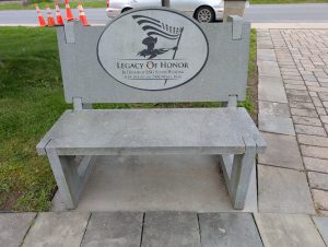 veteran bench | 3i Graphics & Signs Gray memorial bench with a circular plaque reading 'Legacy of Honor' honoring SSG Justin Whiting, KIA January 19, 2008, Mosul, Iraq; orange traffic cones in the background.